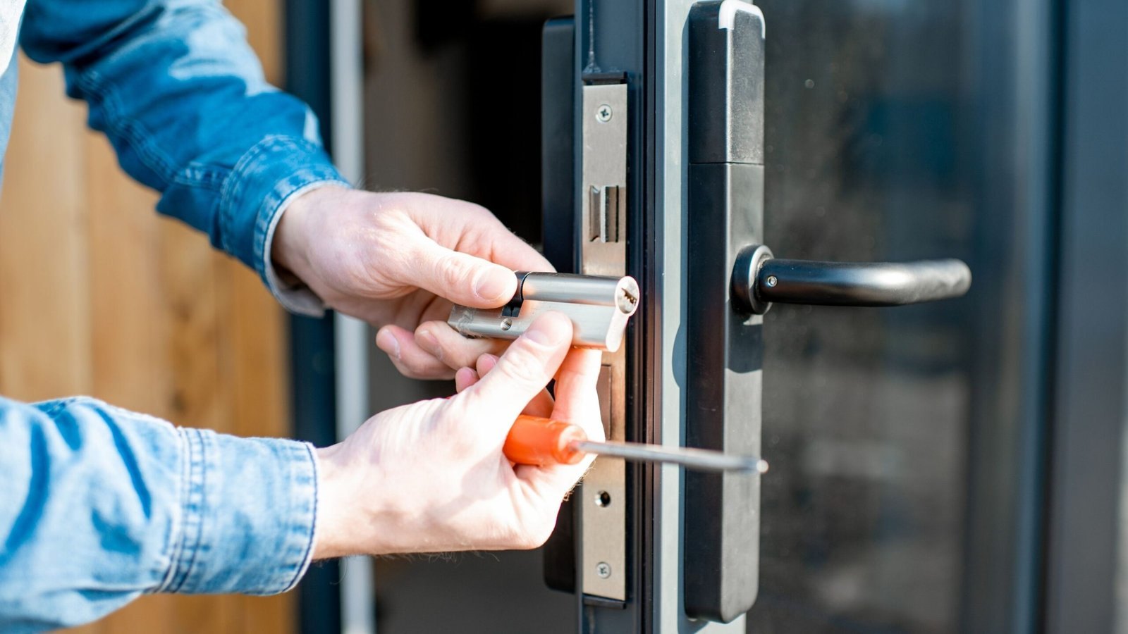 Cerrajero cambiando el cilindro de una cerradura en una puerta de aluminio de un negocio