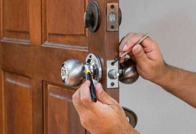 Cerrajero de Cerrajería 24/7 reparando la chapa de una puerta de madera en un domicilio